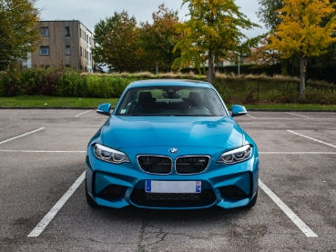 青いBMWが駐車場に正面を向けて停まっている様子